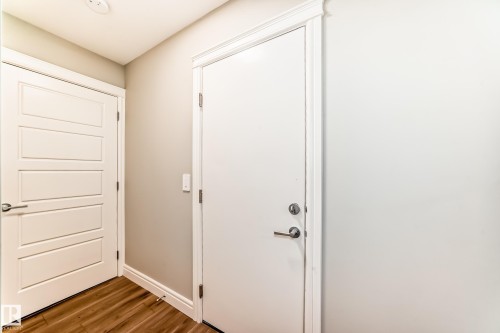 Entryway featuring hardwood-style flooring, white baseboards, and two white doors with modern hardware - 7822 Koruluk Link Link, Edmonton, AB - Indoor Photo Showing Other Room