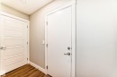 Entryway featuring hardwood-style flooring, white baseboards, and two white doors with modern hardware - 7822 Koruluk Link Link, Edmonton, AB  - Indoor Photo Showing Other Room 
