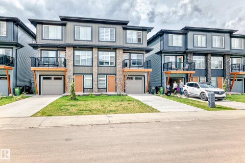 The property features a modern exterior with horizontal siding and stone accents, a private balcony, and an attached garage - 7822 Koruluk Link Link, Edmonton, AB - Outdoor With Balcony With Facade