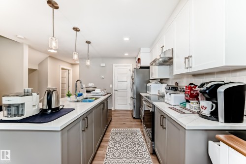 The kitchen features white upper cabinets, grey lower cabinets, and stainless steel appliances - 7822 Koruluk Link Link, Edmonton, AB - Indoor Photo Showing Kitchen