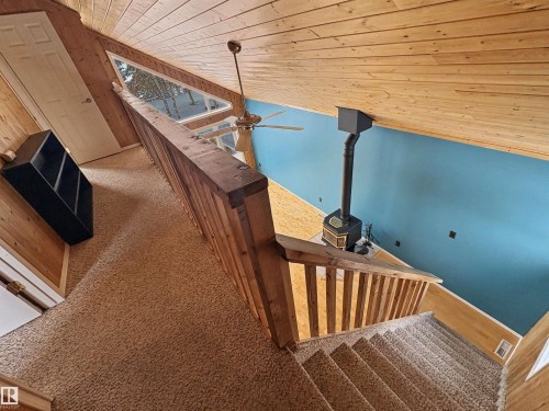 This property features an open interior with wood paneling, a wood-burning stove, and a ceiling fan - #4 Kingbird Road, Rural Bonnyville M.D., AB 