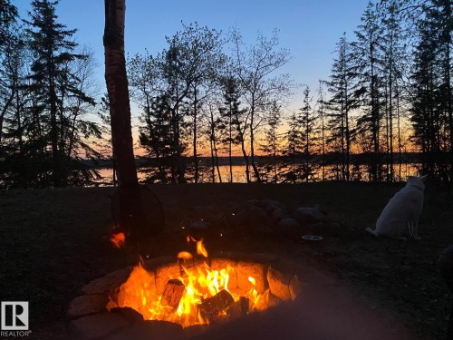 The property features a fire pit with a stone surround, situated on a grassy area - #4 Kingbird Road, Rural Bonnyville M.D., AB 