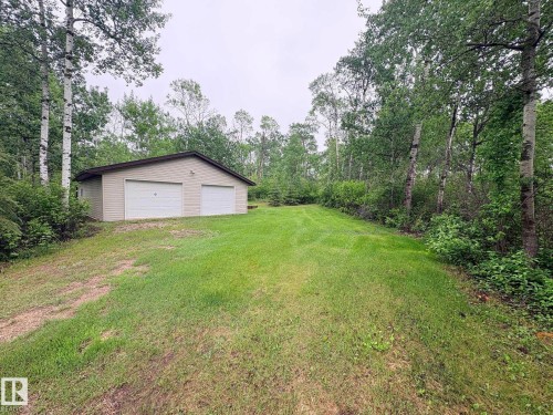 Detached two-car garage with beige vinyl siding and white overhead doors - #4 Kingbird Road, Rural Bonnyville M.D., AB 