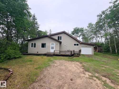 Two-story home with a light-colored siding exterior, an attached garage, a front entry deck, and surrounding mature trees - #4 Kingbird Road, Rural Bonnyville M.D., AB 