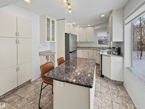 Kitchen featuring white cabinetry, a kitchen island with a dark granite countertop, and tiled flooring - #4 Kingbird Road, Rural Bonnyville M.D., AB 
