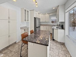 Kitchen featuring white cabinetry, a kitchen island with a dark granite countertop, and tiled flooring - 