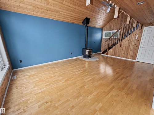 Living area featuring natural wood flooring, a wood-burning stove, and a high vaulted ceiling with natural wood paneling - #4 Kingbird Road, Rural Bonnyville M.D., AB 