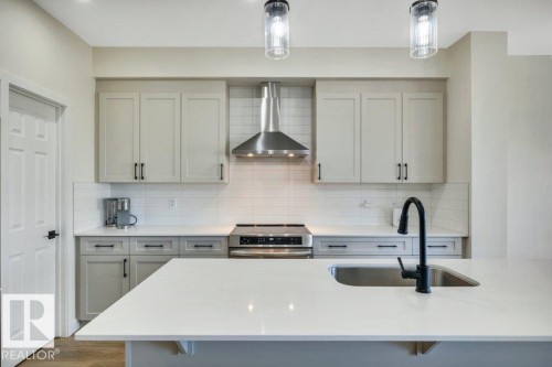The kitchen features light-colored cabinetry, a white subway tile backsplash, and a stainless steel range hood - 13007 213 Street, Edmonton, AB - Indoor Photo Showing Kitchen