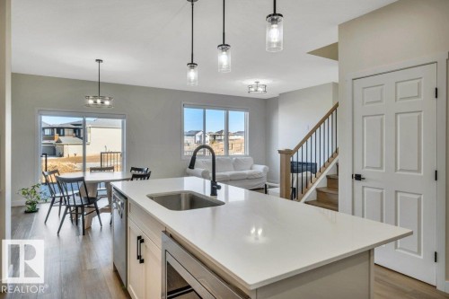 The kitchen features a large island with a sink and modern faucet, pendant lighting, and stainless steel appliances - 13007 213 Street, Edmonton, AB - Indoor Photo Showing Kitchen