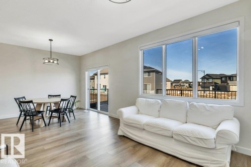 The property features a bright living area with plank flooring, a large window, and a sliding glass door providing access to a deck - 13007 213 Street, Edmonton, AB - Indoor Photo Showing Living Room