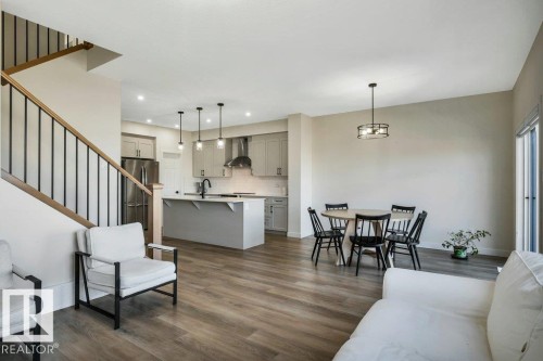 Open concept living area featuring wood-style flooring, a staircase with a wooden handrail and black balusters, and recessed lighting - 13007 213 Street, Edmonton, AB - Indoor Photo Showing Living Room