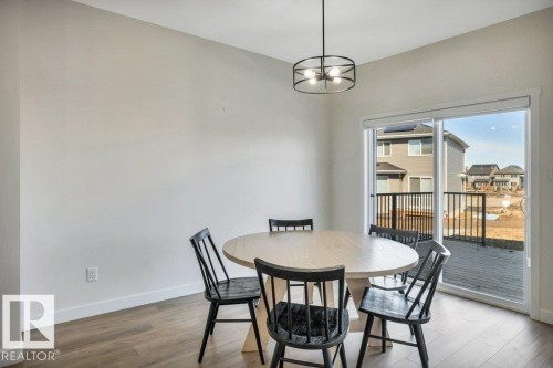Dining area with hardwood style flooring, a contemporary overhead light fixture, and sliding glass doors leading to an outdoor space - 13007 213 Street, Edmonton, AB - Indoor Photo Showing Dining Room