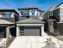 The property features a modern exterior with dark siding and light stone accents, a grey garage door with frosted windows, and a concrete driveway - 13007 213 Street, Edmonton, AB  - Outdoor With Facade 