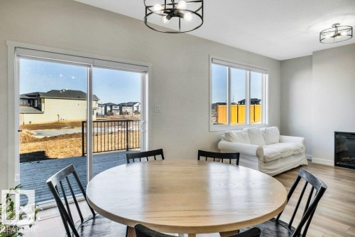 This interior space features a sliding glass door leading to a deck, a round dining table with chairs, and a window providing natural light - 13007 213 Street, Edmonton, AB - Indoor Photo Showing Dining Room
