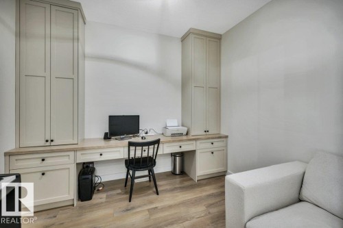This dedicated workspace features light-colored cabinetry with black hardware, a built-in desk, and light wood-style flooring - 13007 213 Street, Edmonton, AB - Indoor Photo Showing Office