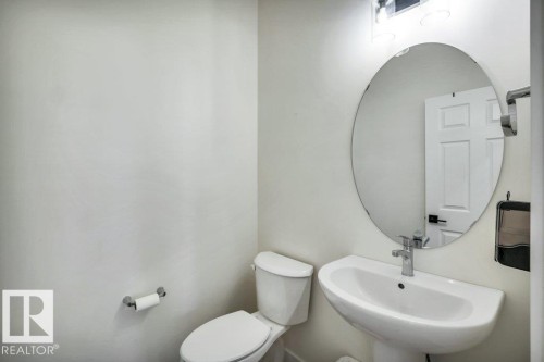 Powder room featuring a pedestal sink, an oval mirror, and a toilet - 13007 213 Street, Edmonton, AB - Indoor Photo Showing Bathroom