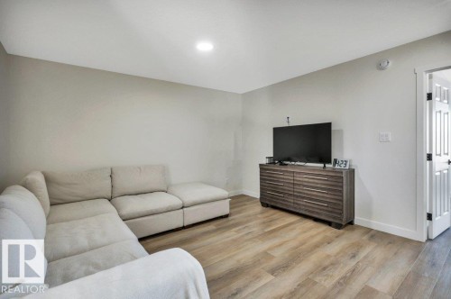 This living area features light-colored walls, recessed ceiling lighting, and wood-style flooring - 13007 213 Street, Edmonton, AB - Indoor Photo Showing Living Room