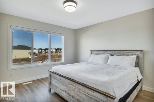 The room features light-colored walls, wood-style flooring, and a large window providing ample natural light - 13007 213 Street, Edmonton, AB - Indoor Photo Showing Bedroom