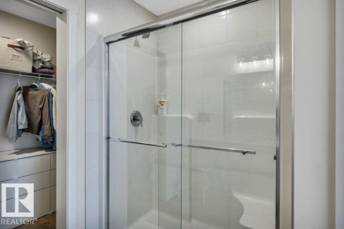 The bathroom features a shower with sliding glass doors, a built-in seat, and tiled walls - 13007 213 Street, Edmonton, AB - Indoor Photo Showing Bathroom