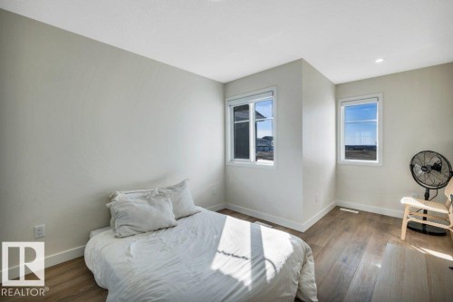 This room features two windows providing natural light, light-colored walls, and hardwood flooring - 13007 213 Street, Edmonton, AB - Indoor Photo Showing Bedroom