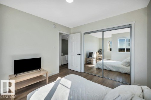 This room features light-colored walls and wood-look flooring, creating a bright and inviting atmosphere - 13007 213 Street, Edmonton, AB - Indoor Photo Showing Bedroom