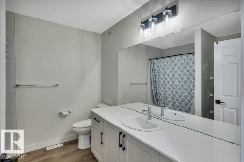 The bathroom features a double vanity with white countertops and undermount sinks, complemented by a large wall-mounted mirror - 13007 213 Street, Edmonton, AB - Indoor Photo Showing Bathroom