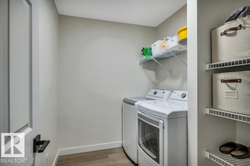 Laundry area featuring a front-loading washing machine, a top-loading washing machine, and wire shelving for storage - 13007 213 Street, Edmonton, AB - Indoor Photo Showing Laundry Room
