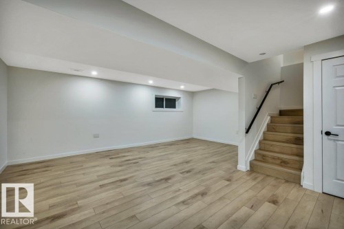 The property features light-toned wood flooring, a white interior door with dark hardware, and a staircase with a dark handrail - 13007 213 Street, Edmonton, AB - Indoor