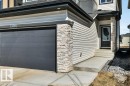 The property features a dark gray garage door, light-colored siding, and stacked stone accents - 13007 213 Street, Edmonton, AB  - Outdoor 