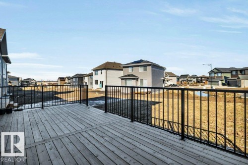 Expansive wood deck with a black metal railing, overlooking the property's yard - 13007 213 Street, Edmonton, AB - Outdoor With Exterior