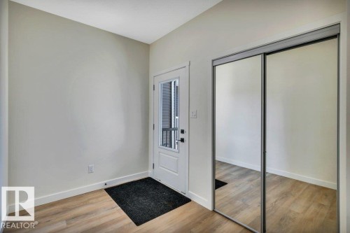 This entry space features light-toned walls, wood-look flooring, and a mirrored sliding closet door - 13007 213 Street, Edmonton, AB - Indoor Photo Showing Other Room