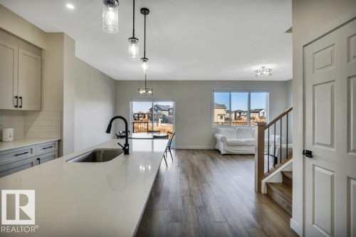 The property features an open-concept living space with a kitchen island, pendant lighting, and large windows providing abundant natural light - 13007 213 Street, Edmonton, AB - Indoor Photo Showing Kitchen With Upgraded Kitchen