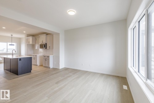 The open-concept living area features light-colored flooring, white walls, and a large window - 3828 38 Street E, Beaumont, AB - Indoor Photo Showing Kitchen With Upgraded Kitchen