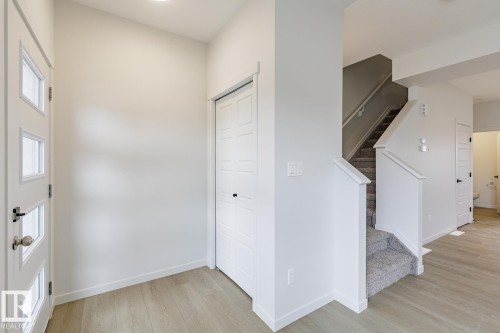 Entryway featuring light wood-style flooring, a white paneled door with glass inserts, and a closet with bifold doors - 3828 38 Street E, Beaumont, AB - Indoor Photo Showing Other Room