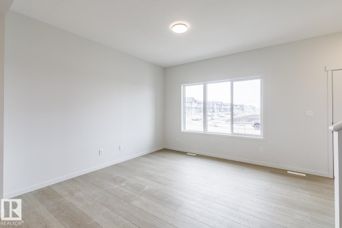 Spacious room featuring light-colored flooring, white walls, and a large window providing natural light - 3828 38 Street E, Beaumont, AB - Indoor Photo Showing Other Room