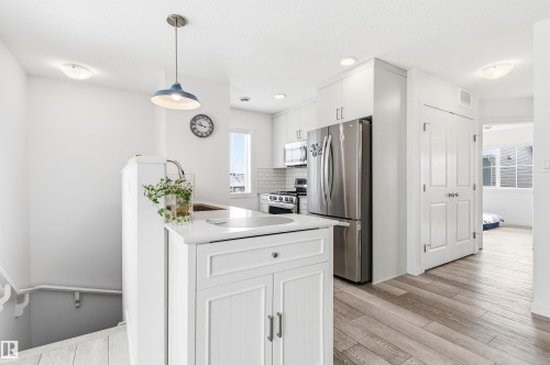 The kitchen features white cabinetry, stainless steel appliances, and a light-colored countertop - 58 1110 Daniels Link Link, Edmonton, AB - Indoor Photo Showing Kitchen