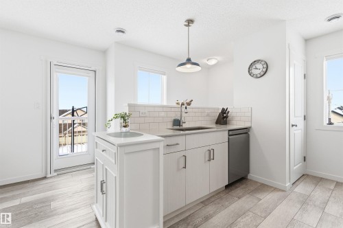 The property features light-colored wood-look flooring and white walls, creating a bright and open atmosphere - 58 1110 Daniels Link Link, Edmonton, AB - Indoor
