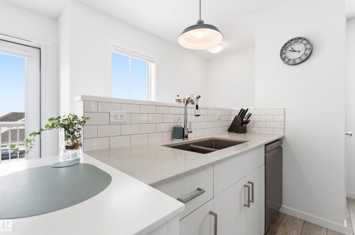 The kitchen features light-colored countertops, a double basin sink with a chrome faucet, and white subway tile backsplash - 58 1110 Daniels Link Link, Edmonton, AB - Indoor Photo Showing Kitchen With Double Sink
