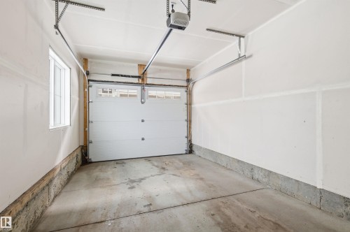 The property features a garage with a concrete floor, white walls, and a window providing natural light - 58 1110 Daniels Link Link, Edmonton, AB - Indoor Photo Showing Garage