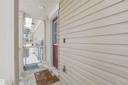 The property features a durable vinyl siding exterior and a red front door with a window panel - 58 1110 Daniels Link Link, Edmonton, AB - Outdoor With Exterior