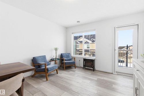 The living area features light-toned flooring, a large window, and a door leading to an exterior balcony - 58 1110 Daniels Link Link, Edmonton, AB - Indoor