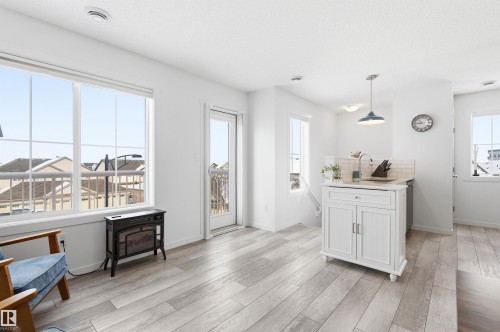 This bright, open concept living area features light-toned flooring, large windows, and a glass-paneled door opening to a balcony - 58 1110 Daniels Link Link, Edmonton, AB - Indoor