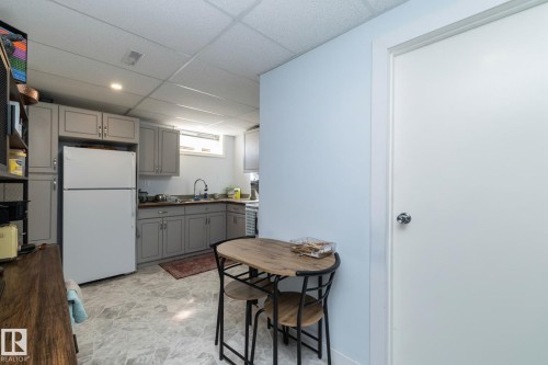 The kitchen features gray cabinetry, a white refrigerator, and a stainless steel sink - 12 Mill Drive, St. Albert, AB - Indoor Photo Showing Kitchen