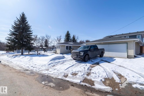 The property features a two-car garage with a white door and a paved driveway - 12 Mill Drive, St. Albert, AB - Outdoor