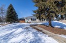 The property features a concrete walkway leading to the front entrance, a sloped front yard with a lawn, and mature evergreen trees - 12 Mill Drive, St. Albert, AB  - Outdoor 