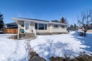 The property features a concrete exterior, a white entry door with a storm door, and a white railing leading to the entrance - 12 Mill Drive, St. Albert, AB  - Outdoor With Facade 