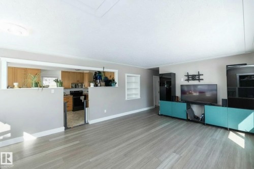 The property features a spacious living area with light-toned flooring and neutral wall colors - 12 Mill Drive, St. Albert, AB - Indoor Photo Showing Other Room