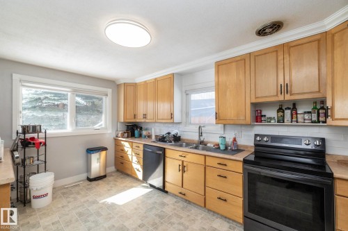 The kitchen features wood cabinetry, a tiled floor, and a double window - 12 Mill Drive, St. Albert, AB - Indoor Photo Showing Kitchen With Double Sink