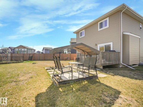 The property features a spacious backyard with a lawn, a wooden fence, and a patio area - 3910 49 Avenue, Beaumont, AB - Outdoor