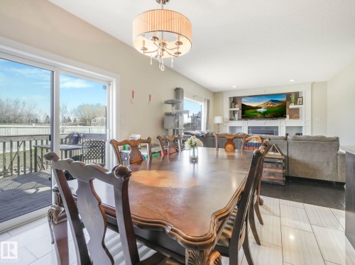 The property features an open-concept living area with a decorative chandelier, tile flooring, and a sliding glass door leading to an outdoor deck - 3910 49 Avenue, Beaumont, AB - Indoor Photo Showing Dining Room
